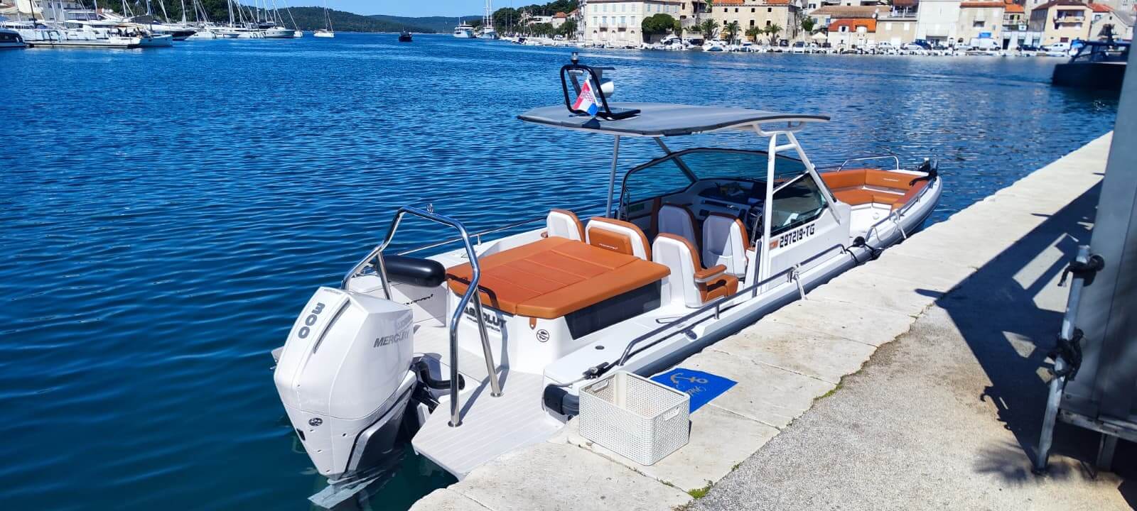 Axopar 28 T-Top liegt im Yachthafen von Trogir mit Küstenstadt und roten Dächern auf der anderen Seite der Bucht – Avangard Charter-Bootsverleih Dalmatien Kroatien