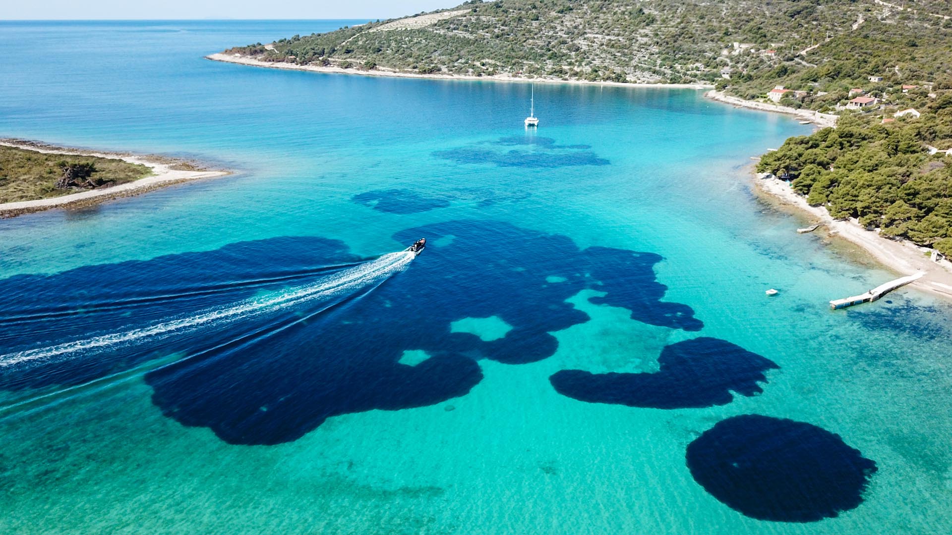 Luftaufnahme der Blue Lagoon mit kristallklarem Adriawasser, Speedboot und Segelboot in der Ferne – Avangard Charter Bootstouren Kroatien